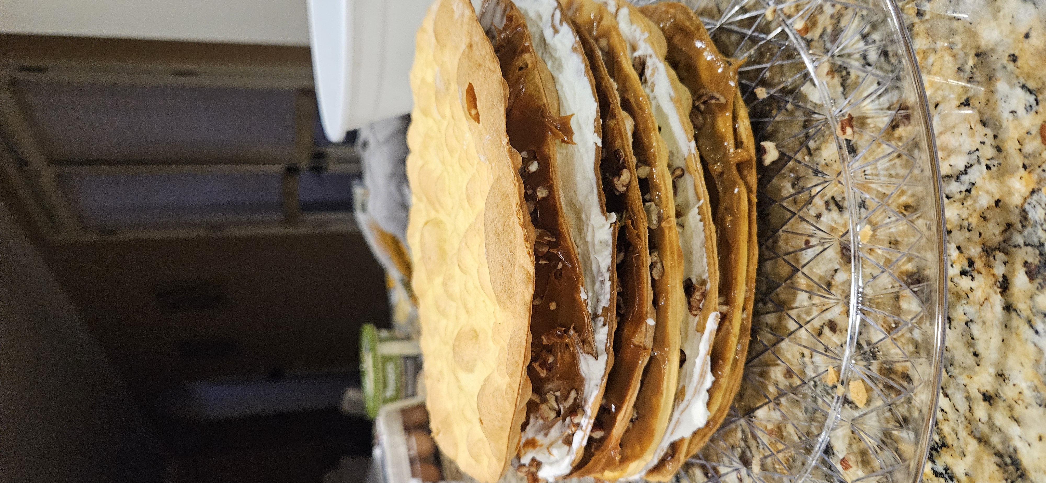 Capas de hojarasca armándose a mano con manjar, nuez y crema en la cocina de Dulce Chile